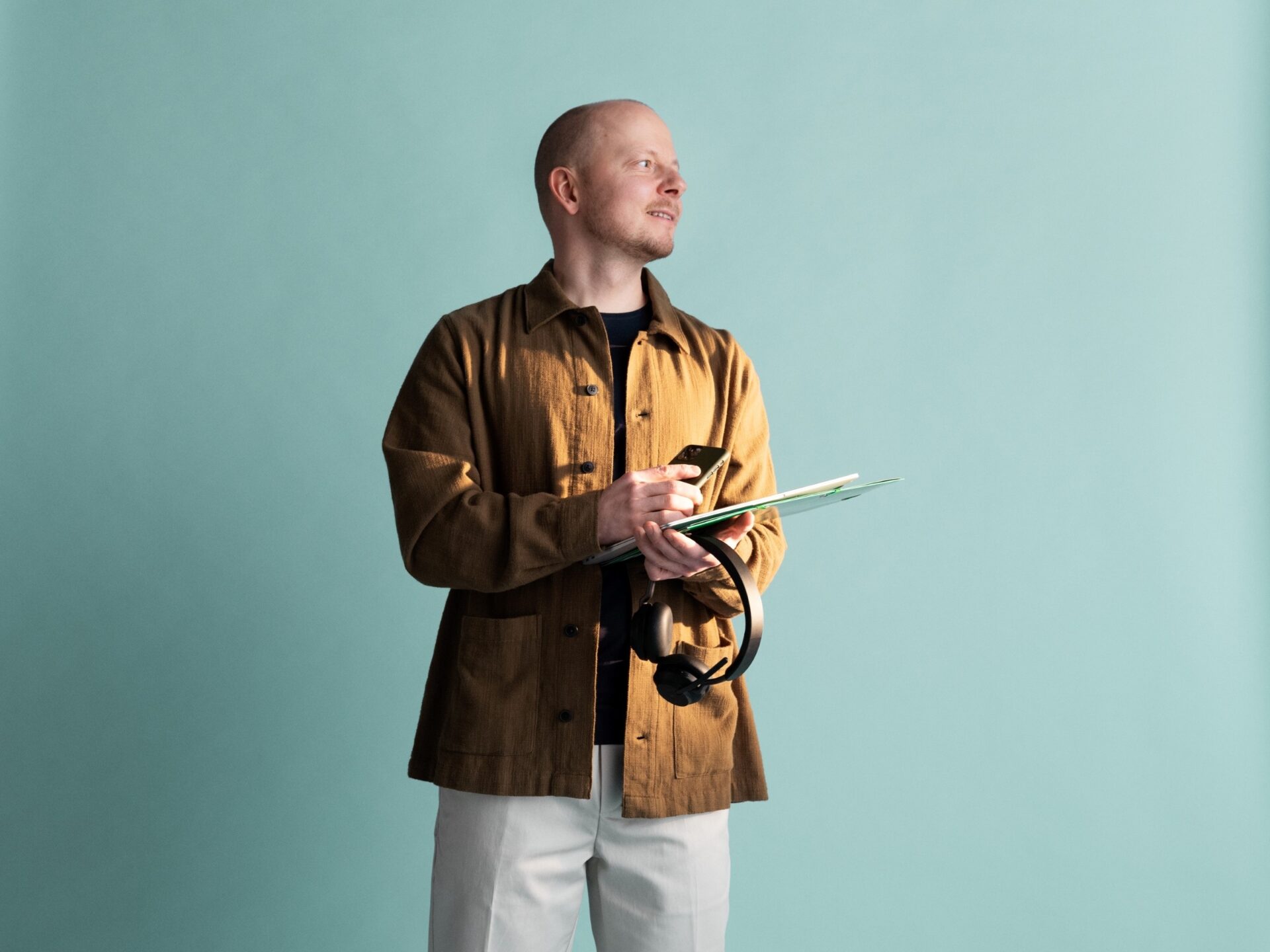 seisova mies läppäri puhelin ja kuulokkeet kädessä