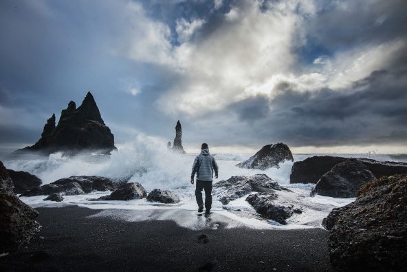 Mies kävelee myrskyisän meren rannalla